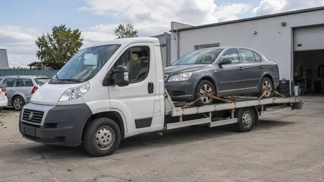 Bílý odtahový vůz s upevněným vozidlem Škoda na hliníkové plošině