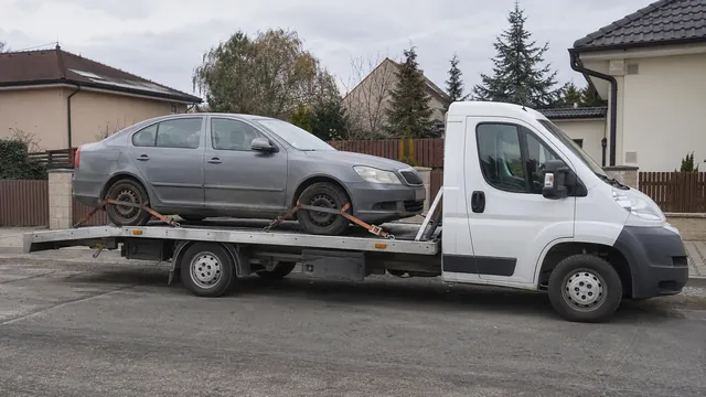 Bílý odtahový vůz s upevněným vozidlem Škoda na hliníkové plošině