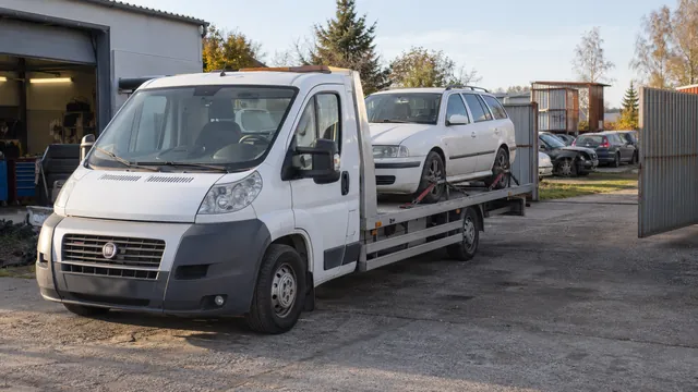 Bílý odtahový vůz s upevněným vozidlem Škoda na hliníkové plošině