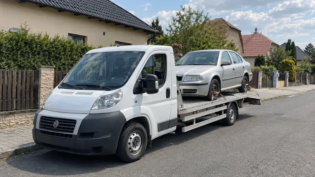 Bílý odtahový vůz s upevněným vozidlem Škoda na hliníkové plošině