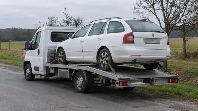 Bílý odtahový vůz s upevněným vozidlem Škoda na hliníkové plošině