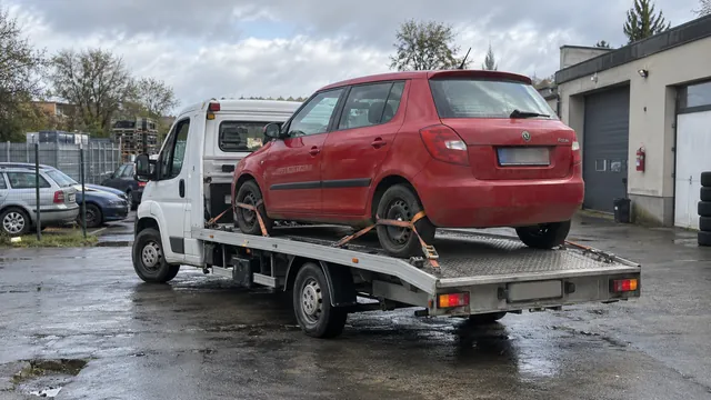 Bílý odtahový vůz s upevněným vozidlem Škoda na hliníkové plošině