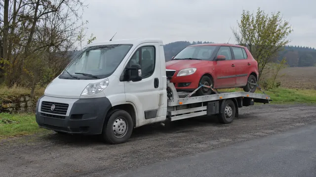 Bílý odtahový vůz s upevněným vozidlem Škoda na hliníkové plošině