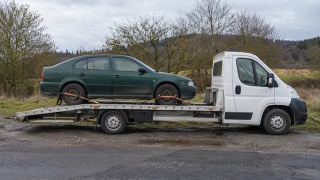 Bílý odtahový vůz s upevněným vozidlem Škoda na hliníkové plošině