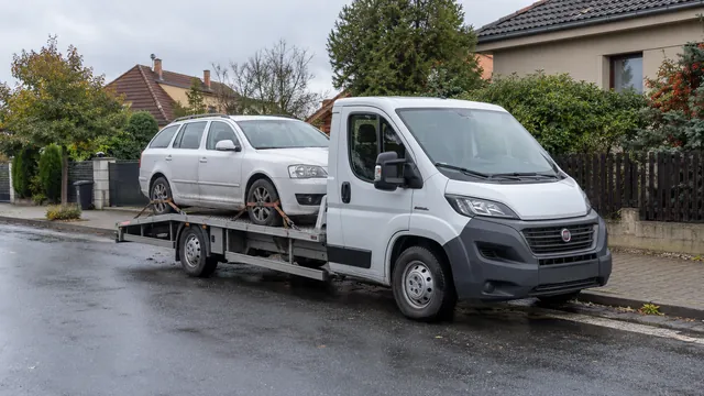 Bílý odtahový vůz s upevněným vozidlem Škoda na hliníkové plošině
