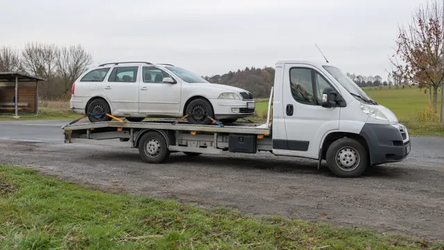 Bílý odtahový vůz s upevněným vozidlem Škoda na hliníkové plošině