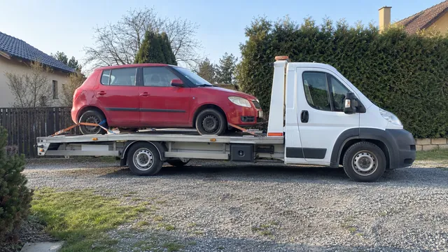 Bílý odtahový vůz s upevněným vozidlem Škoda na hliníkové plošině