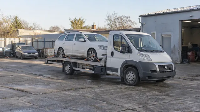 Bílý odtahový vůz s upevněným vozidlem Škoda na hliníkové plošině