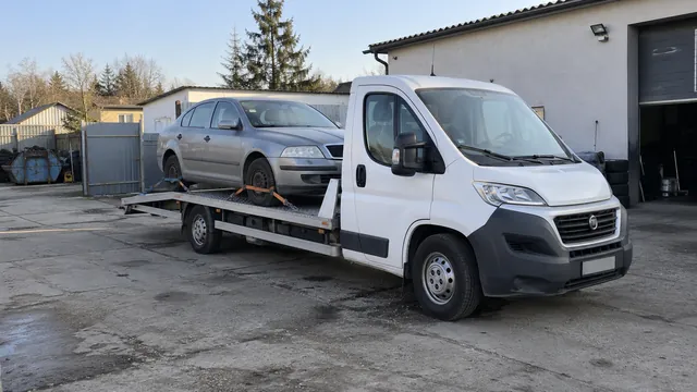 Bílý odtahový vůz s upevněným vozidlem Škoda na hliníkové plošině