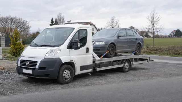 Bílý odtahový vůz s upevněným vozidlem Škoda na hliníkové plošině