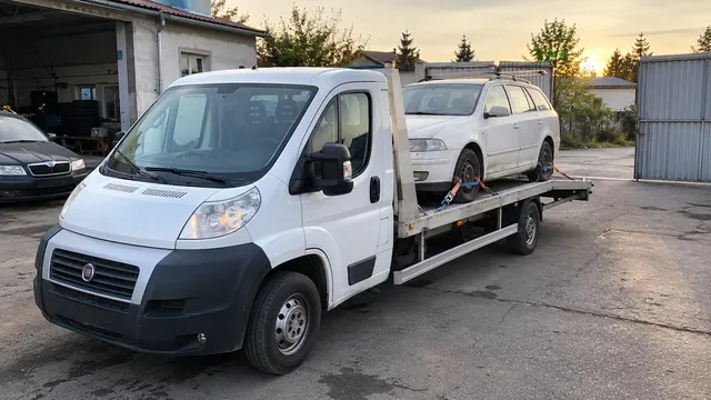 Bílý odtahový vůz s upevněným vozidlem Škoda na hliníkové plošině